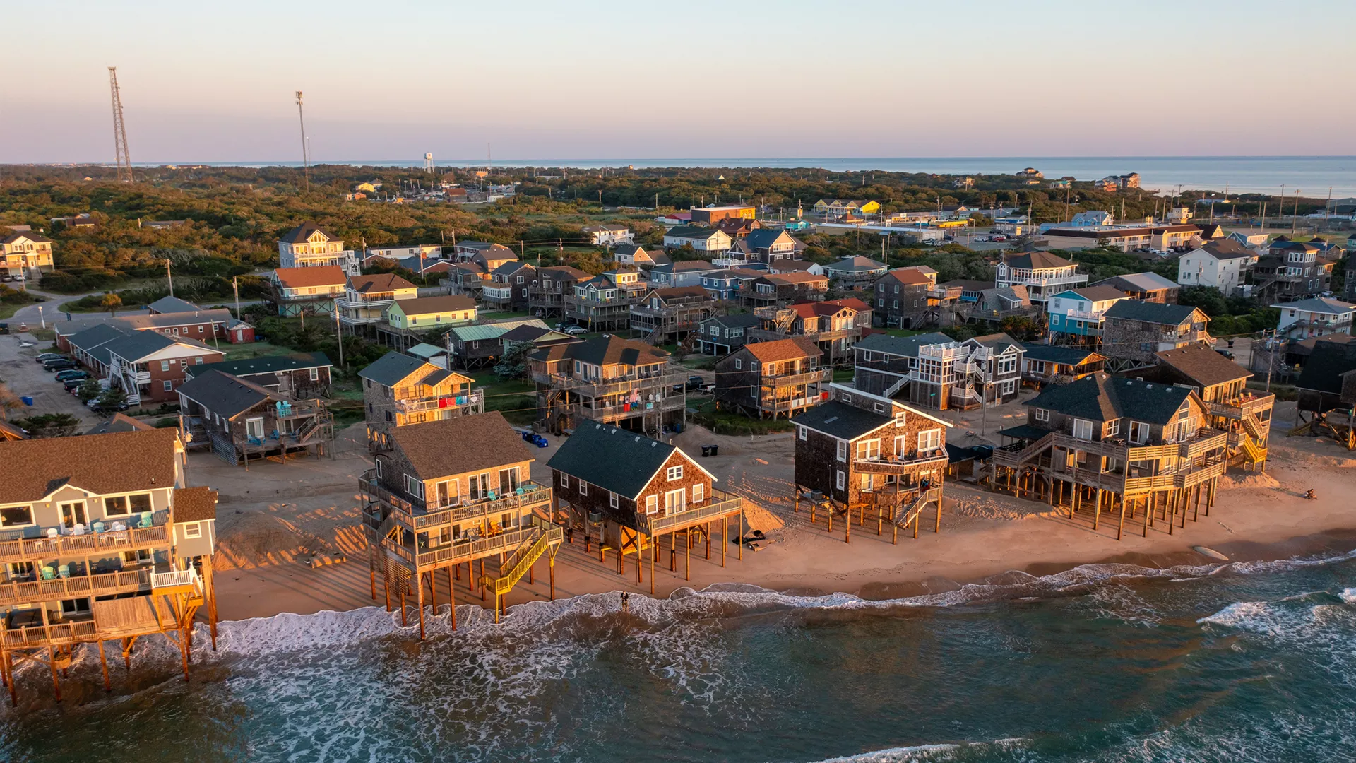 Image of a coast with houses on stilts during a sunset.