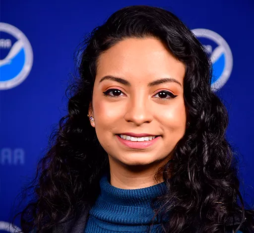 Bonnie Acosta smiling in front of a NOAA step and repeat.